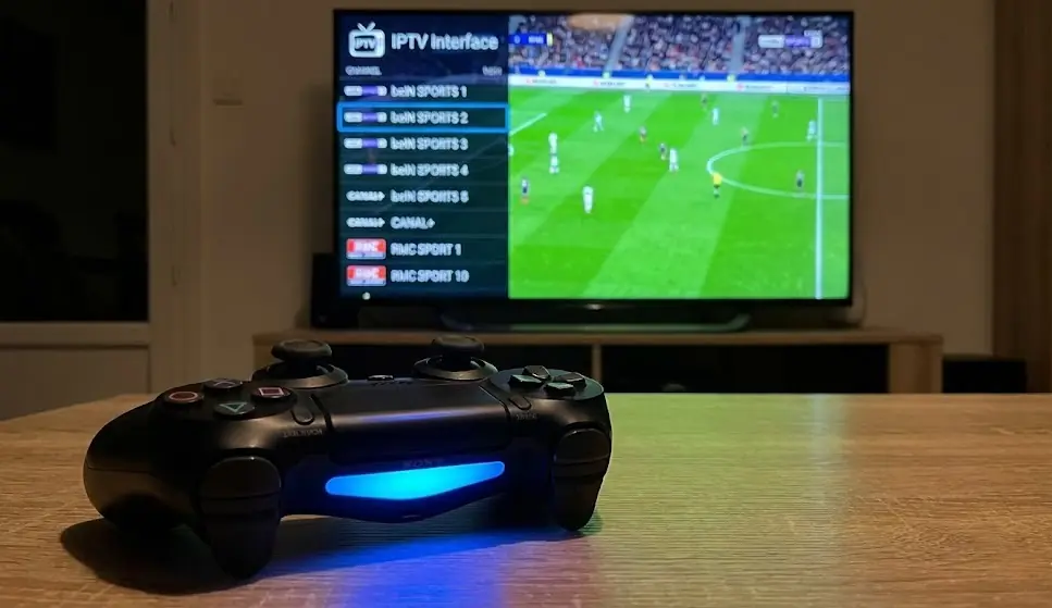 Manette DualShock 4 avec écran TV diffusant un match de foot en arrière-plan